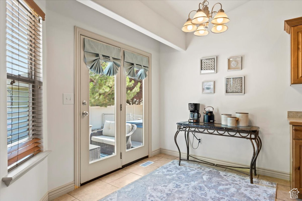 Entryway with a chandelier, light tile patterned floors, and lofted ceiling