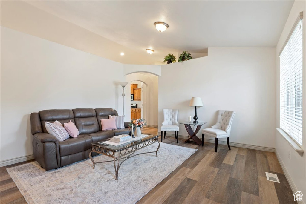 Living area featuring arched walkways, wood finished floors, and healthy amount of natural light