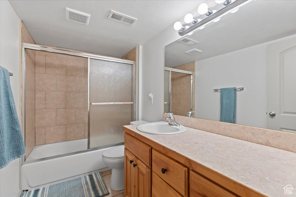 Full bath with vanity, shower / bath combination with glass door, and tile patterned flooring