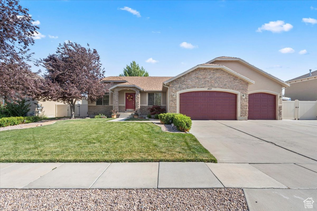 View of front facade featuring a garage, stone siding, driveway, and stucco siding