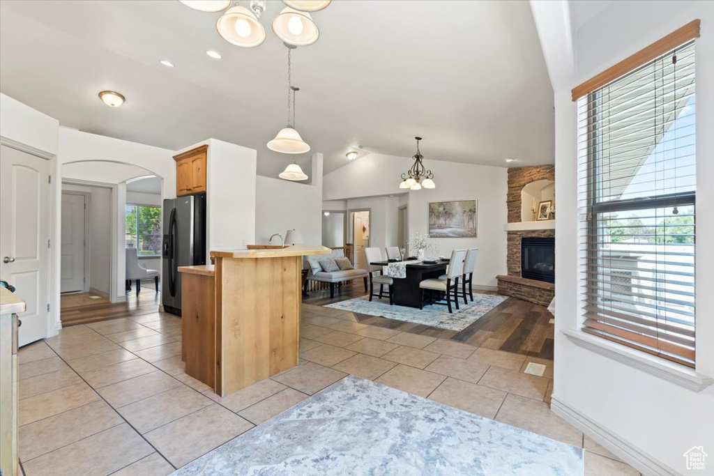 Kitchen featuring a chandelier, vaulted ceiling, fridge with ice dispenser, arched walkways, and open floor plan