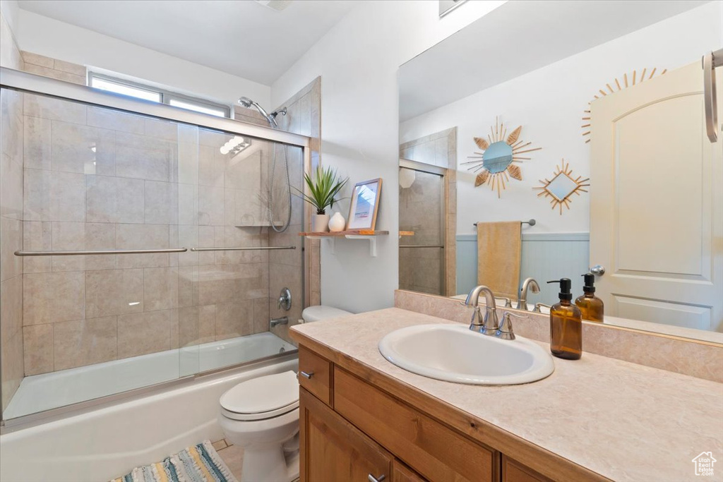 Bathroom featuring vanity, enclosed tub / shower combo, and wainscoting