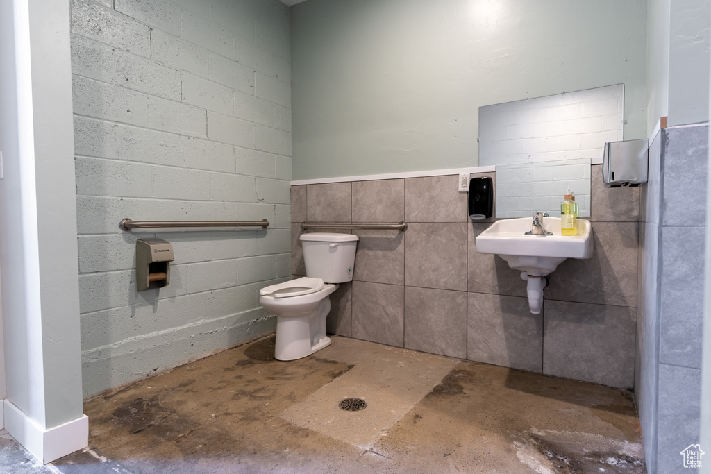 Half bathroom with toilet and unfinished concrete flooring