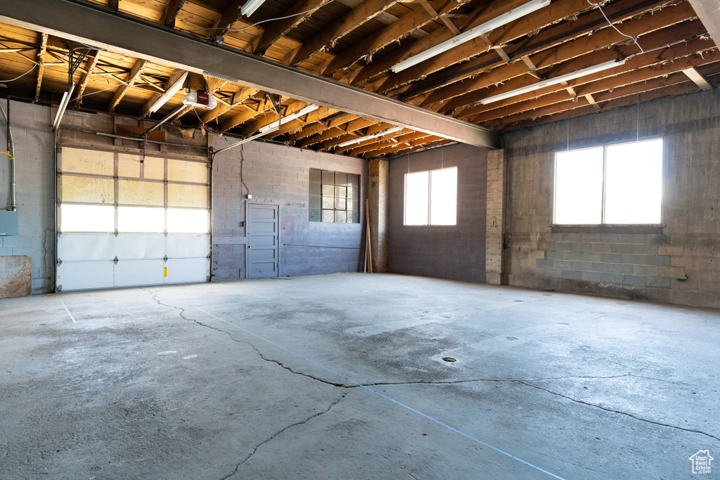 Garage featuring a garage door opener and concrete block wall
