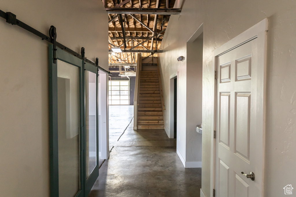 Hall with a barn door, concrete floors, and a towering ceiling