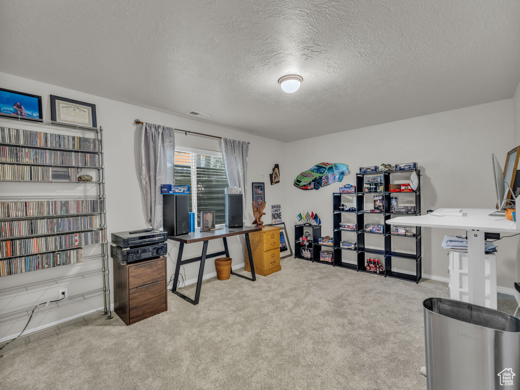 Carpeted office space featuring a textured ceiling and baseboards