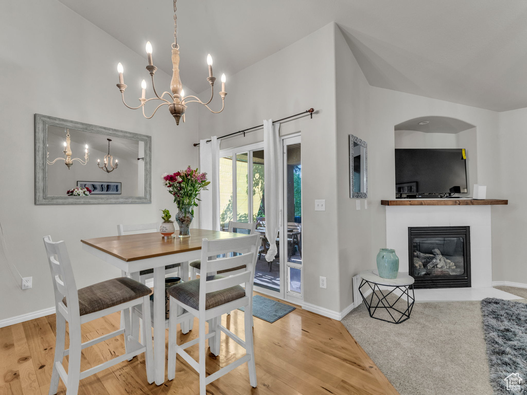 Dining space with a chandelier, wood finished floors, and a glass covered fireplace