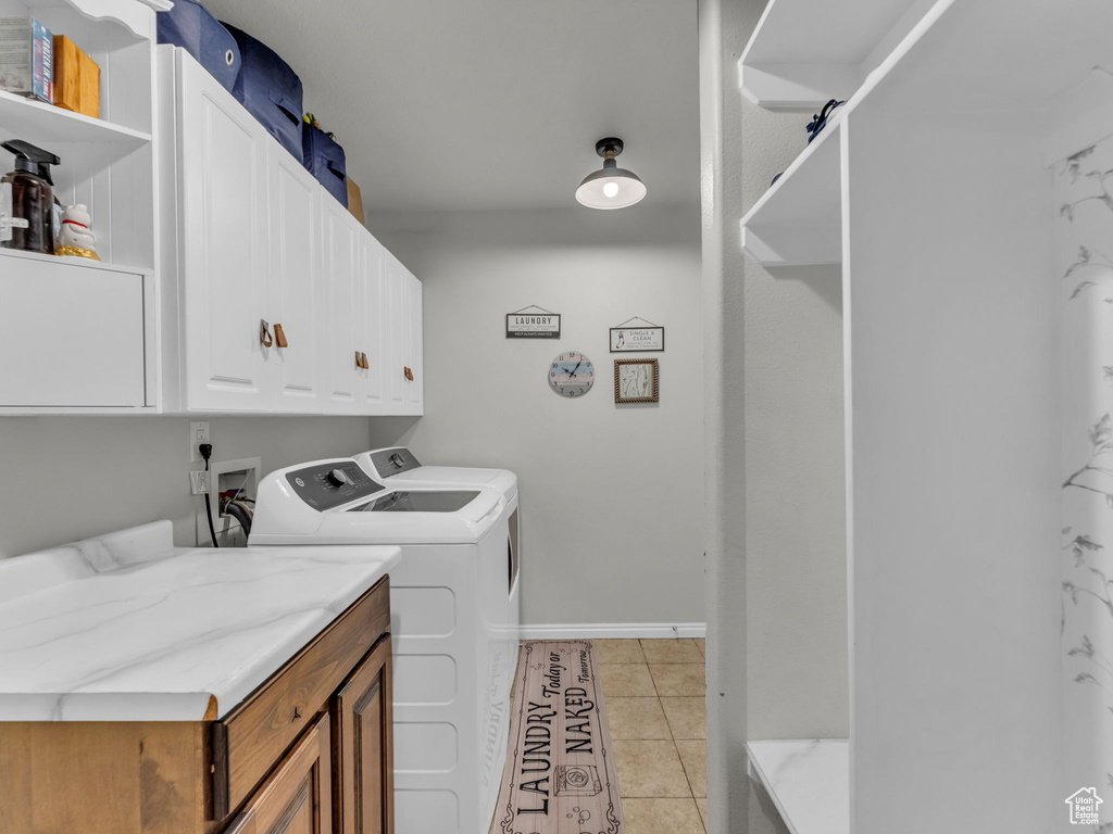 Laundry room with cabinet space, washer and clothes dryer, and light tile patterned flooring