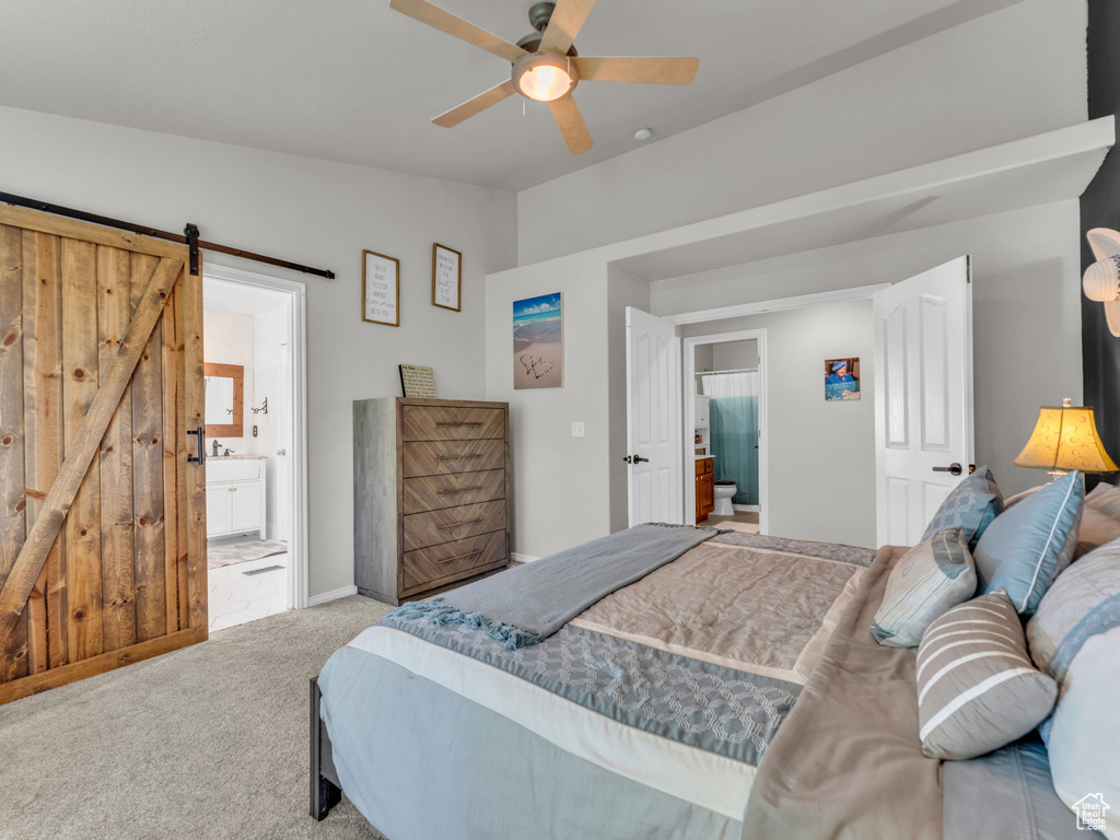 Bedroom featuring carpet flooring, ensuite bath, a barn door, a ceiling fan, and vaulted ceiling