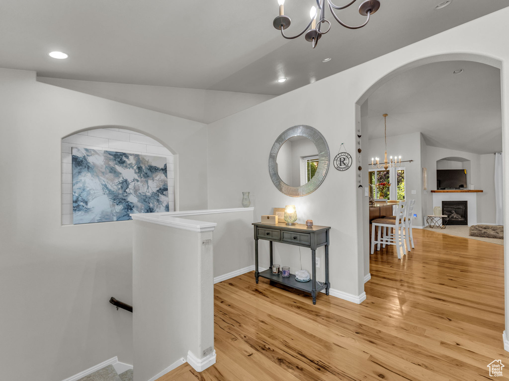 Hall featuring a chandelier, an upstairs landing, light wood-style flooring, arched walkways, and recessed lighting