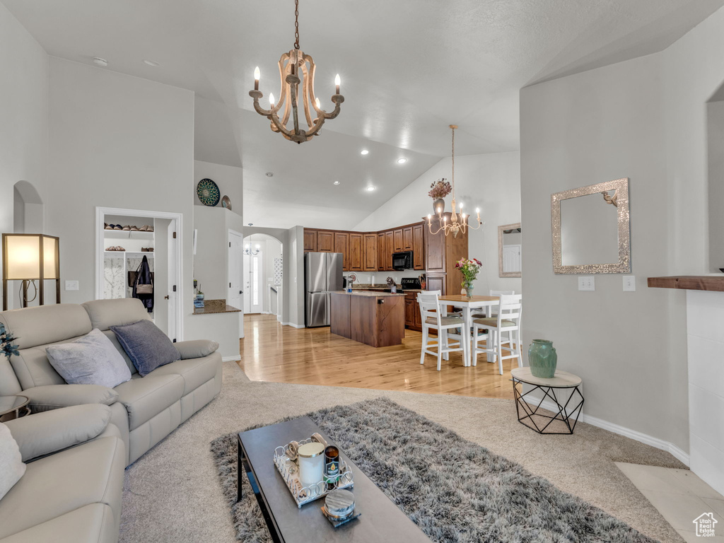 Living room featuring a chandelier, arched walkways, high vaulted ceiling, and light colored carpet