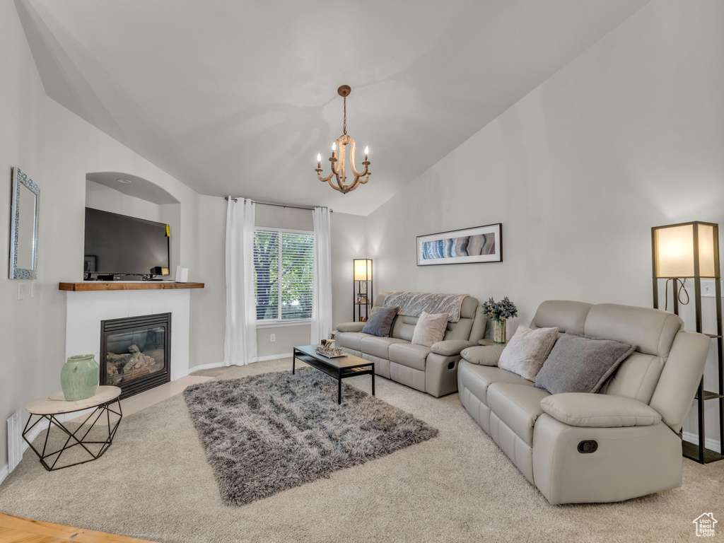 Carpeted living room featuring lofted ceiling, a chandelier, and a fireplace with flush hearth