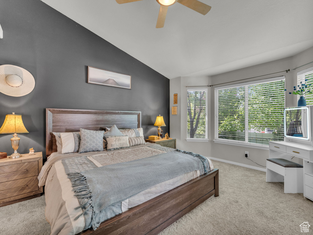 Carpeted bedroom featuring multiple windows, lofted ceiling, and a ceiling fan