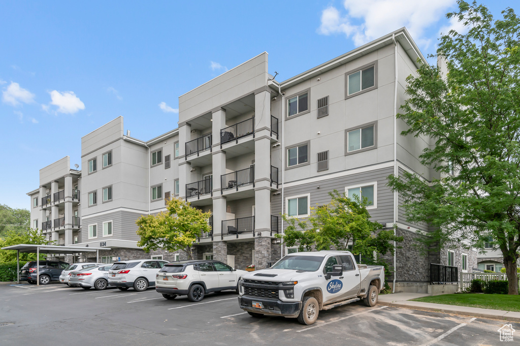 View of apartment building / complex featuring uncovered parking