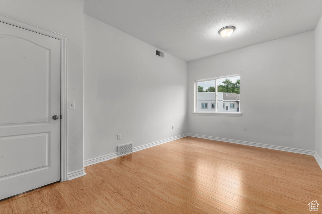 Empty room featuring light wood finished floors and a textured ceiling
