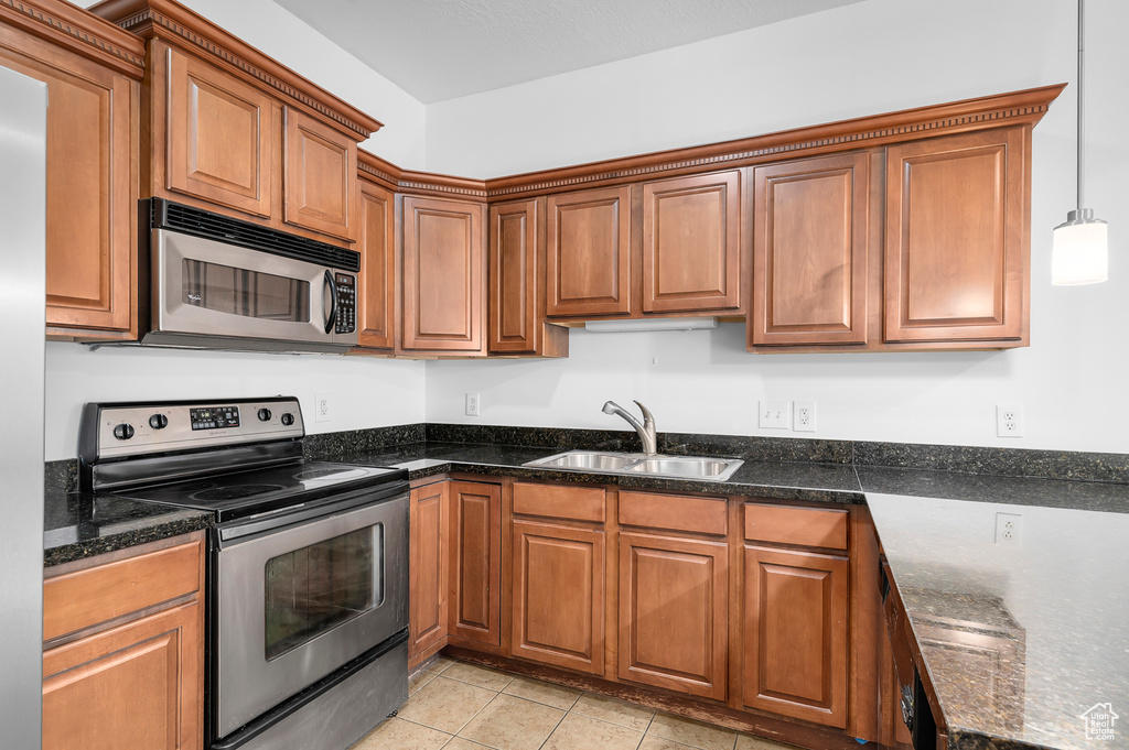 Kitchen featuring appliances with stainless steel finishes, brown cabinetry, and dark stone counters