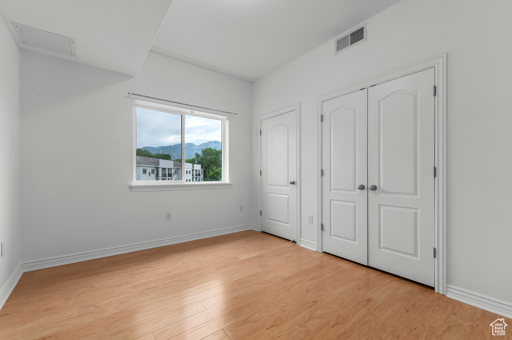 Unfurnished bedroom featuring light wood-style floors and a mountain view