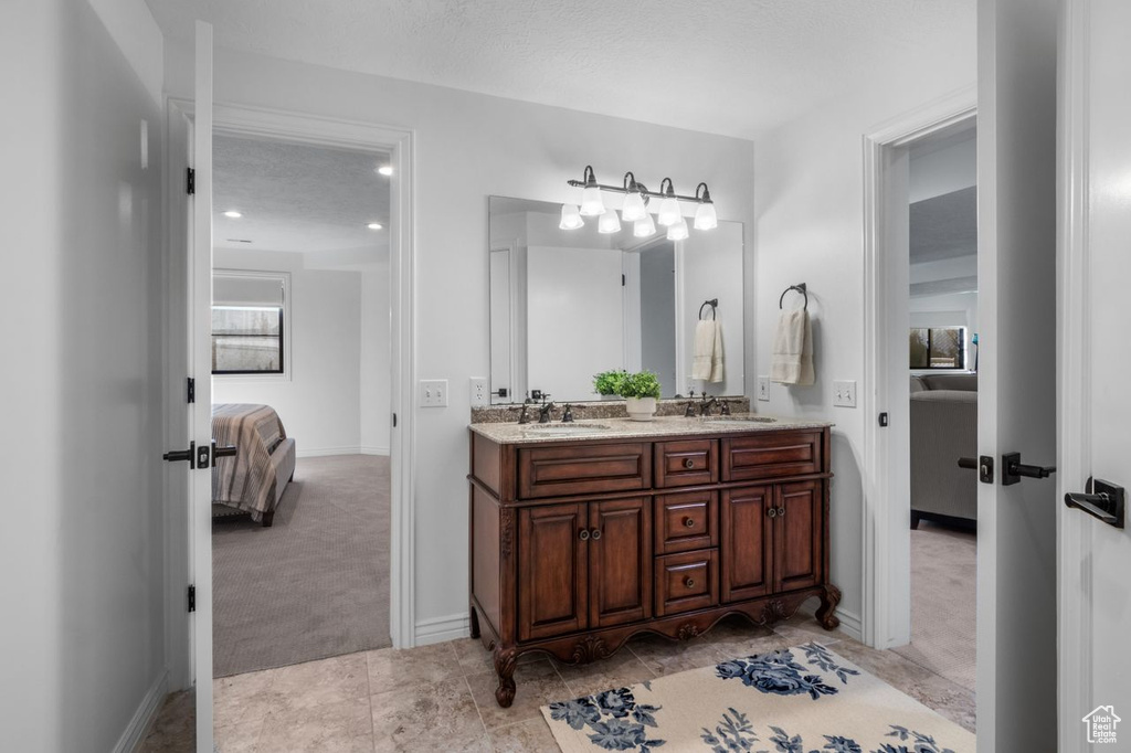 Ensuite bathroom featuring double vanity and baseboards