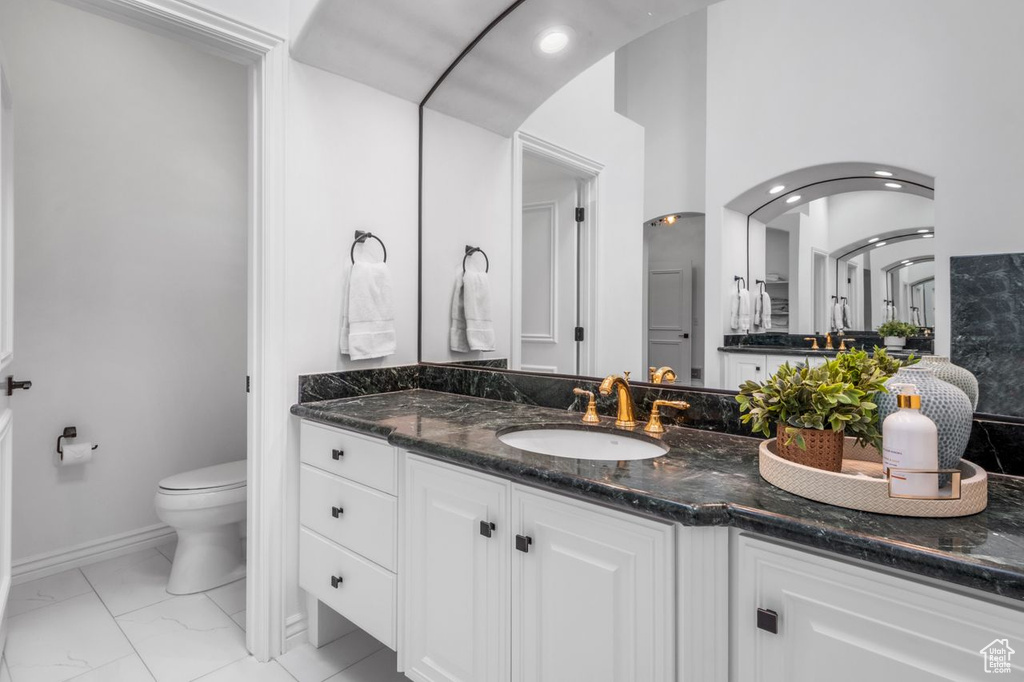Bathroom featuring vanity, marble look tile flooring, and recessed lighting