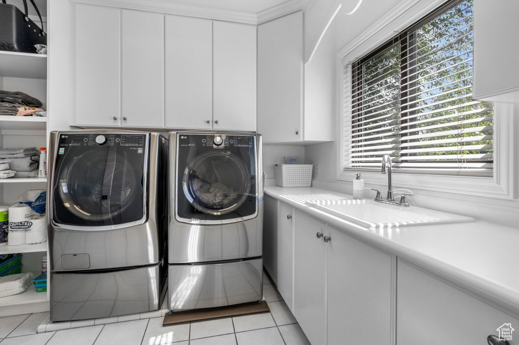 Washroom featuring cabinet space, washer and clothes dryer, and light tile patterned flooring