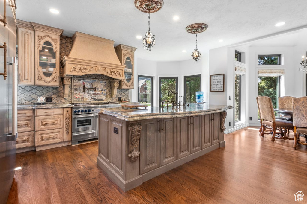 Kitchen with premium appliances, premium range hood, a chandelier, dark wood finished floors, and recessed lighting