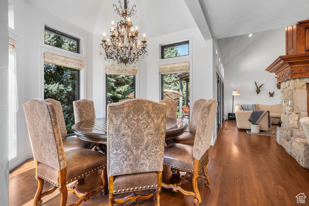 Dining area featuring high vaulted ceiling, a chandelier, and wood finished floors