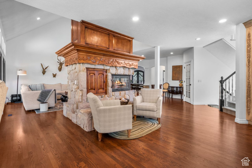 Living area with stairs, dark wood-type flooring, a fireplace, recessed lighting, and lofted ceiling