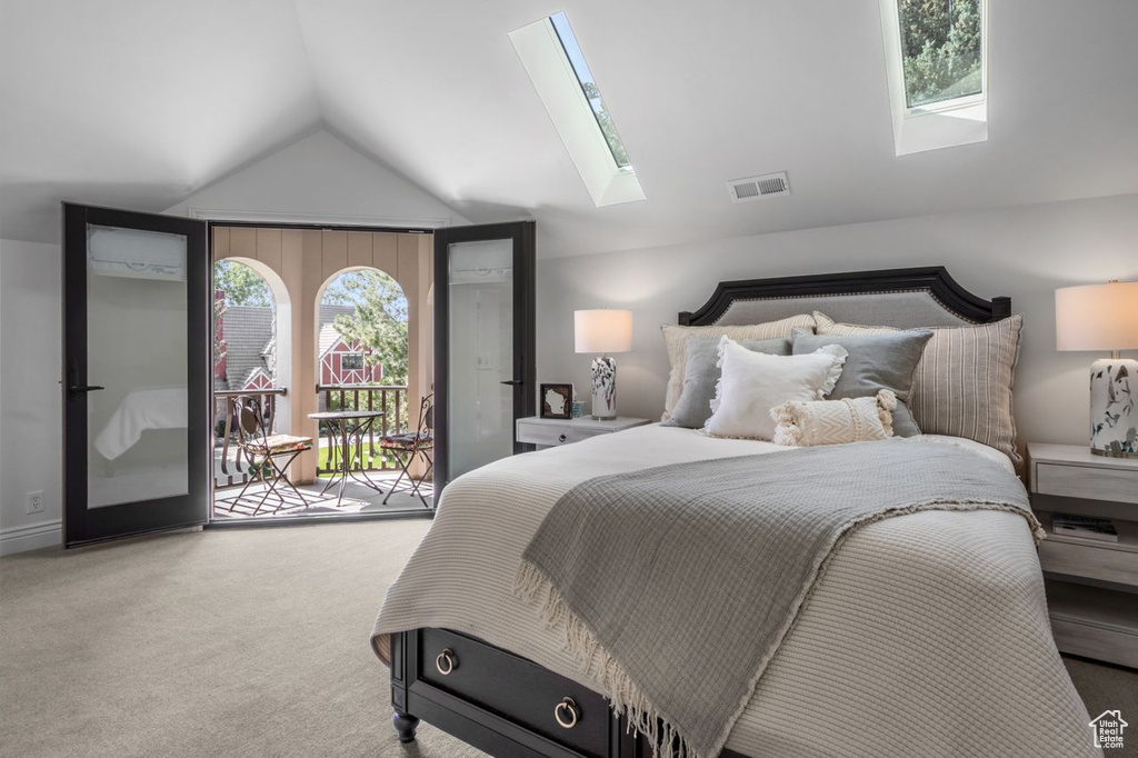 Bedroom featuring a skylight, access to exterior, vaulted ceiling, carpet flooring, and multiple windows