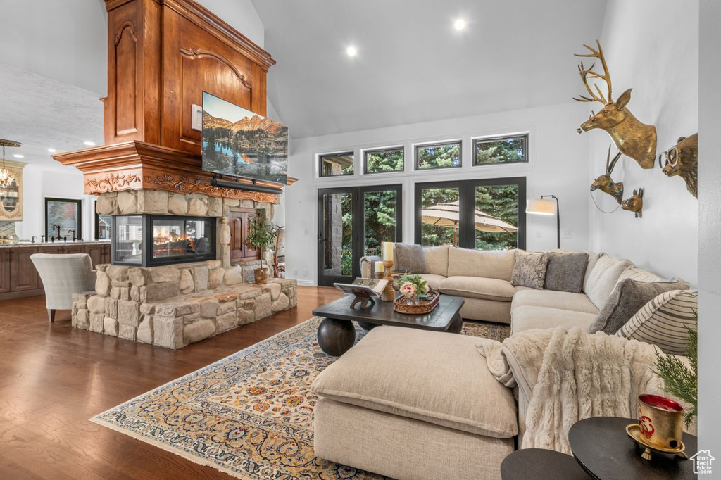 Living area with high vaulted ceiling, wood finished floors, a fireplace, and recessed lighting