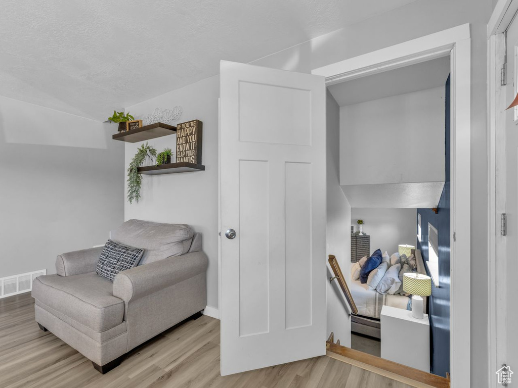 Living area featuring wood finished floors, an upstairs landing, a textured ceiling, and lofted ceiling