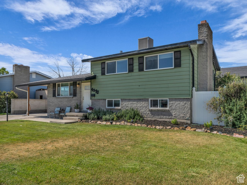 Rear view of house featuring a chimney, an attached carport, and a patio