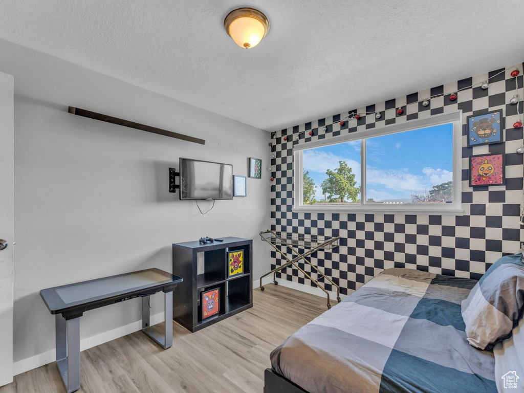 Bedroom featuring a textured ceiling, wood finished floors, and an accent wall