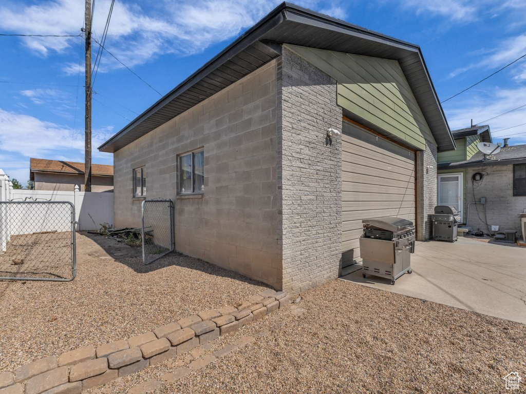 View of property exterior with a garage and a patio area