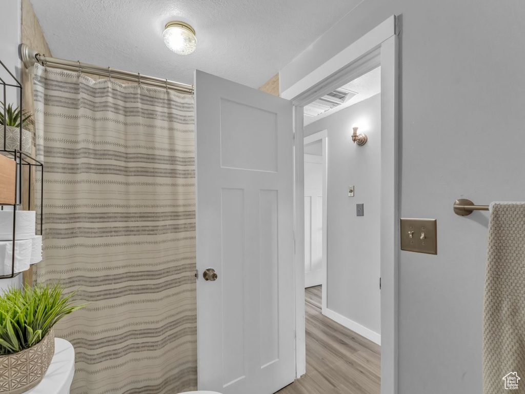 Bathroom with wood finished floors and curtained shower