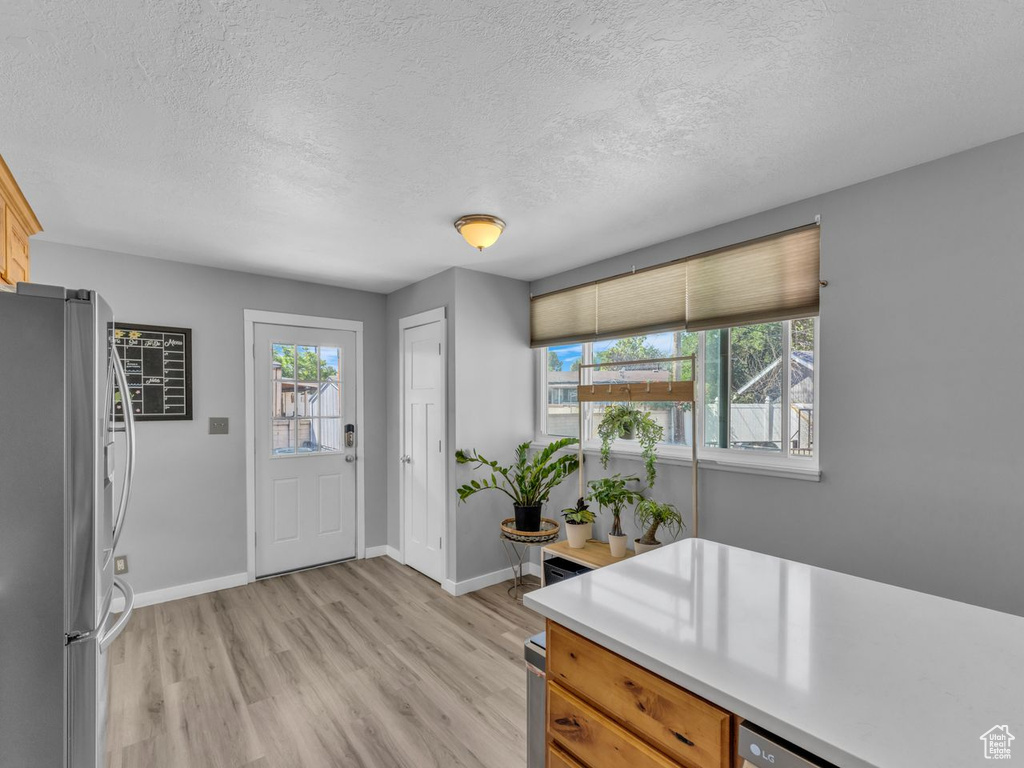 Entrance foyer with light wood-style floors, a textured ceiling, and plenty of natural light