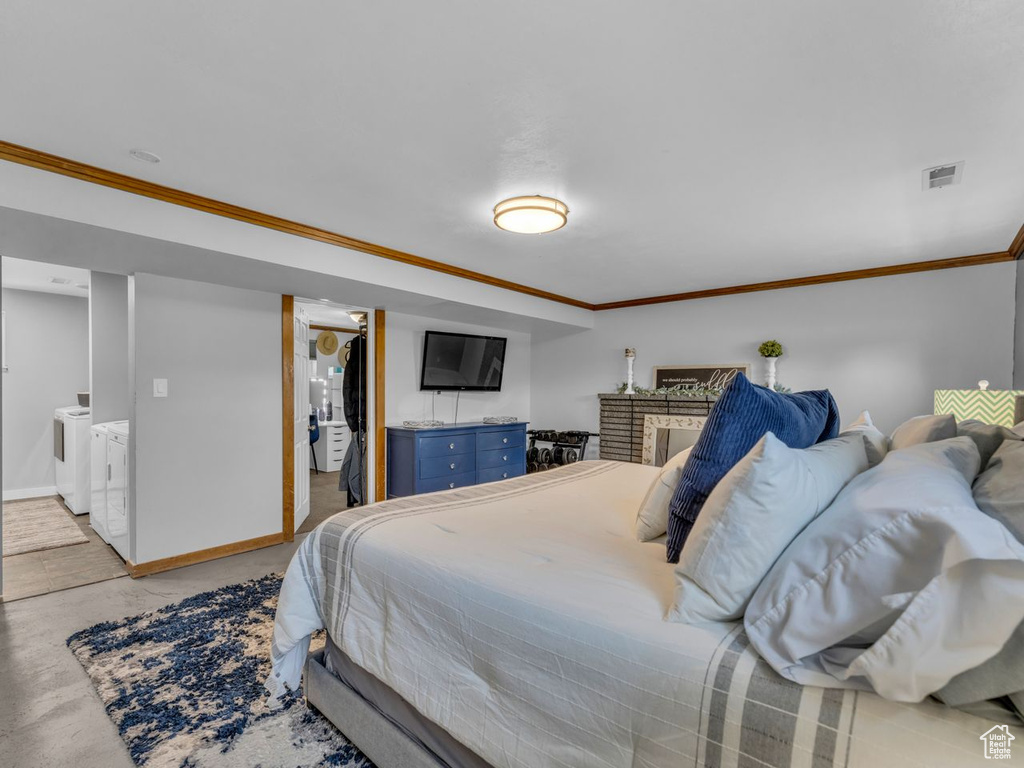 Bedroom with ornamental molding, a fireplace, and separate washer and dryer