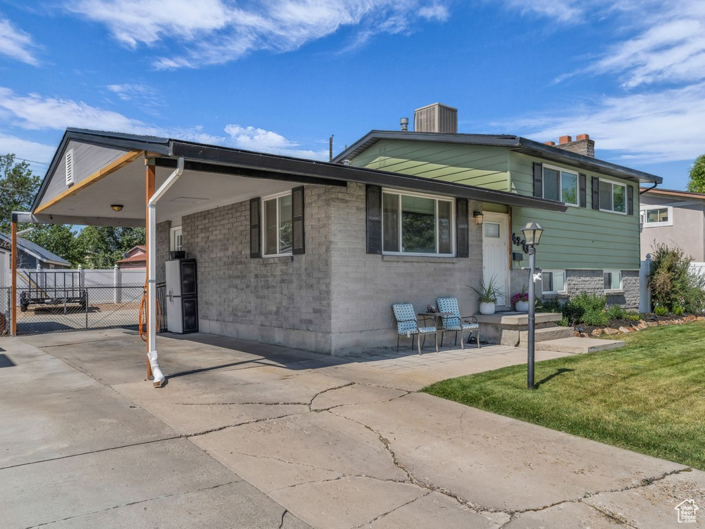 View of front of property with a chimney, a carport, concrete driveway, brick siding, and a gate