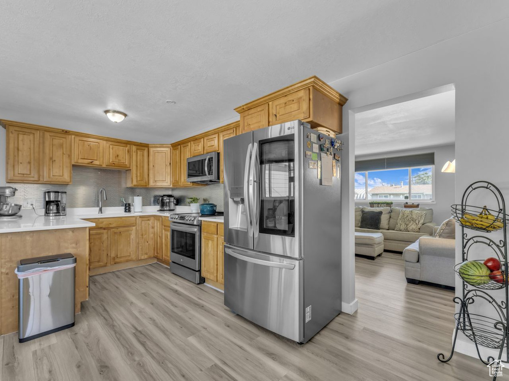 Kitchen with stainless steel appliances, light wood-style floors, and light countertops