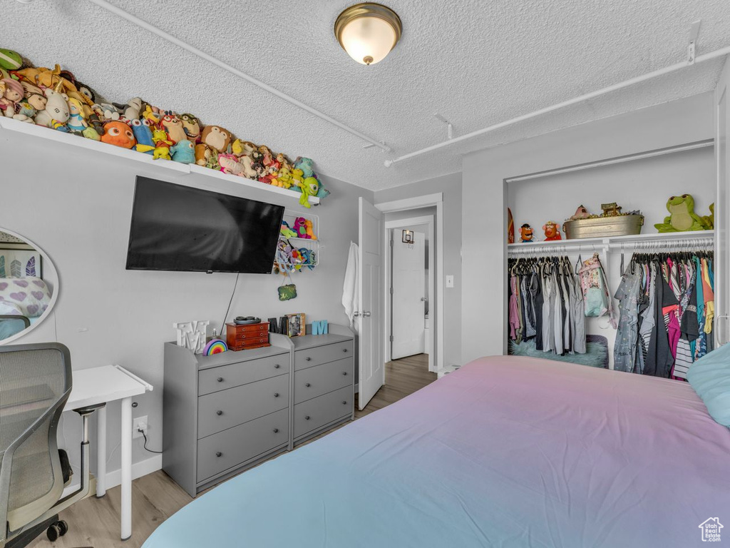 Bedroom featuring wood finished floors, a closet, and a textured ceiling