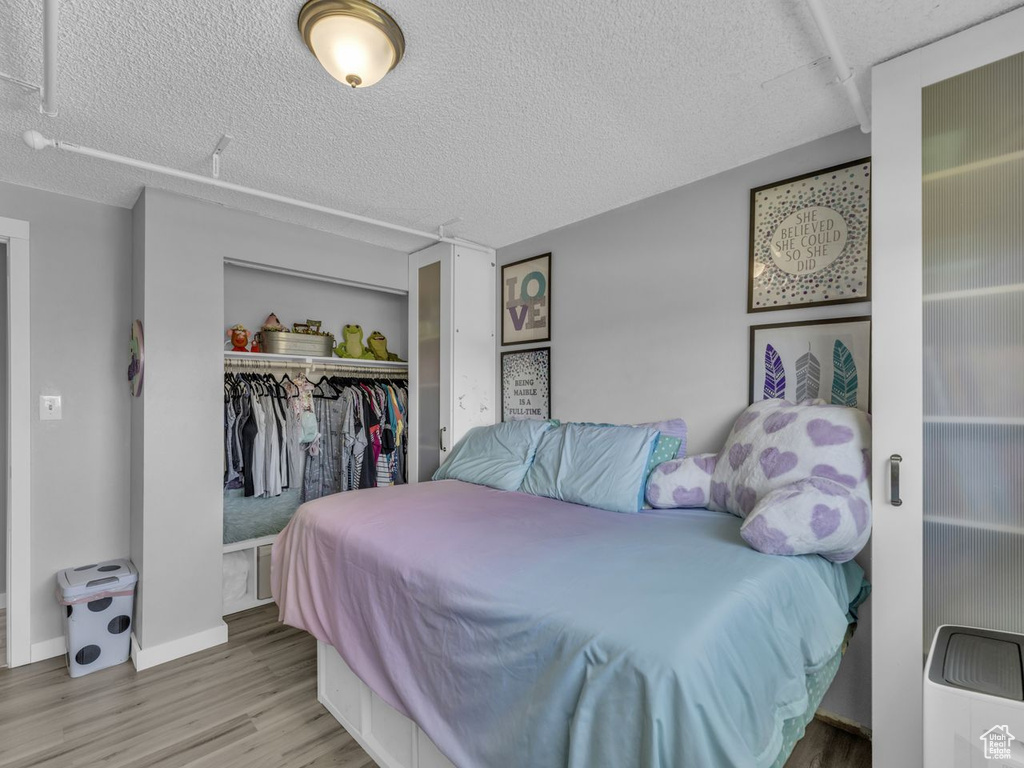 Bedroom featuring wood finished floors, a closet, and a textured ceiling