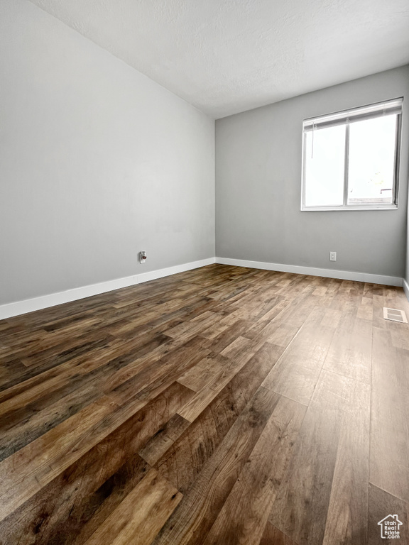 Unfurnished room with dark wood-style flooring and a textured ceiling