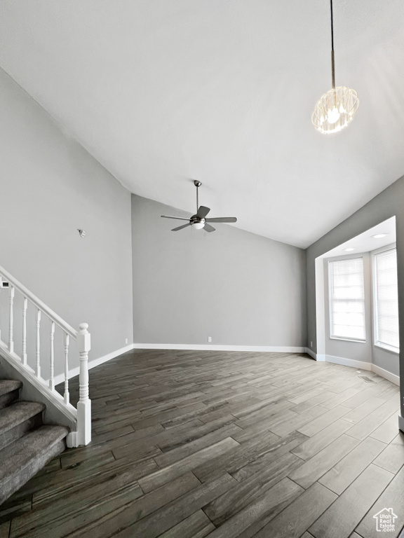 Unfurnished living room with lofted ceiling, wood finished floors, a ceiling fan, stairway, and a chandelier