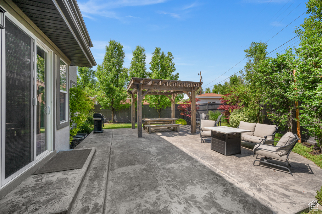 Fenced backyard featuring a pergola, a patio, and an outdoor living space with a fire pit