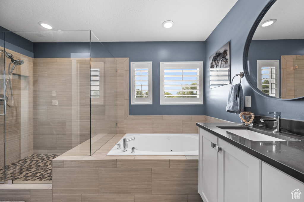 Bathroom featuring vanity, a whirlpool tub, healthy amount of natural light, and a shower stall