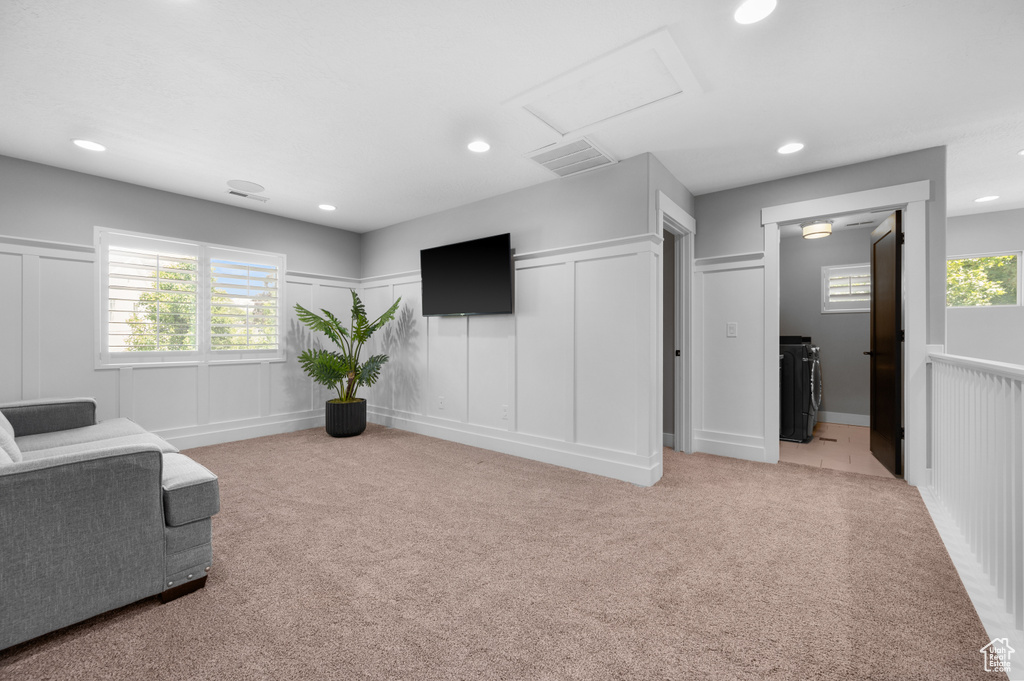 Living area with light carpet, attic access, recessed lighting, and a decorative wall