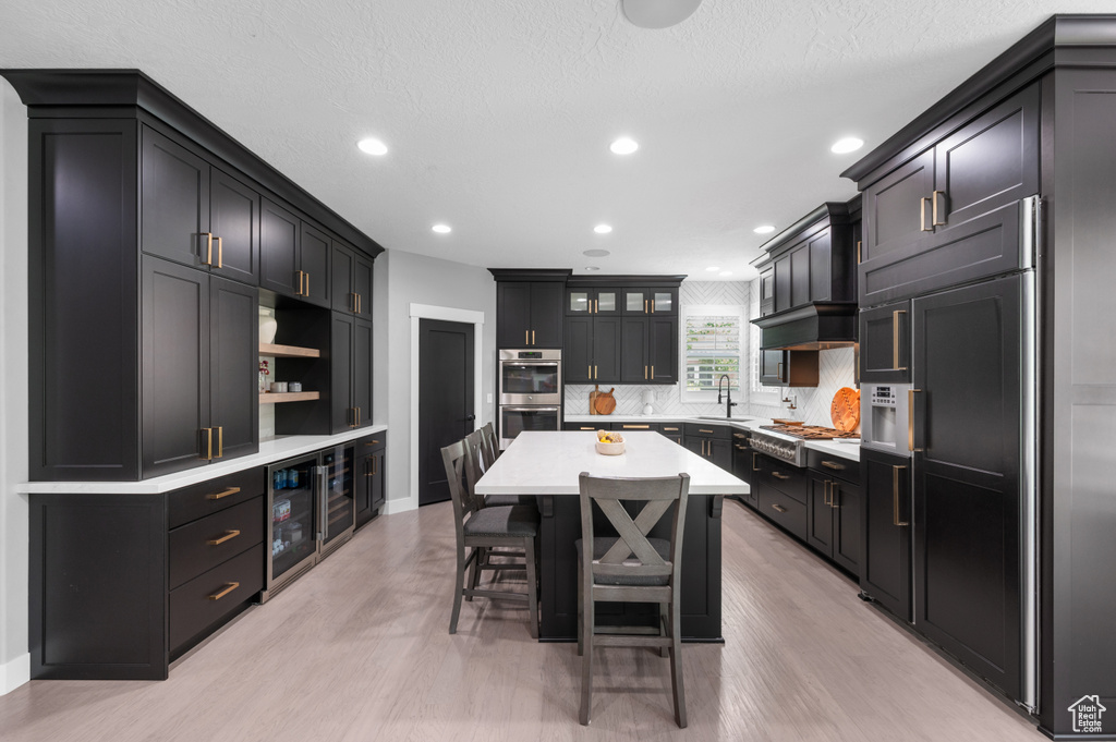 Kitchen with stainless steel appliances, light wood-style flooring, a breakfast bar, a kitchen island, and recessed lighting