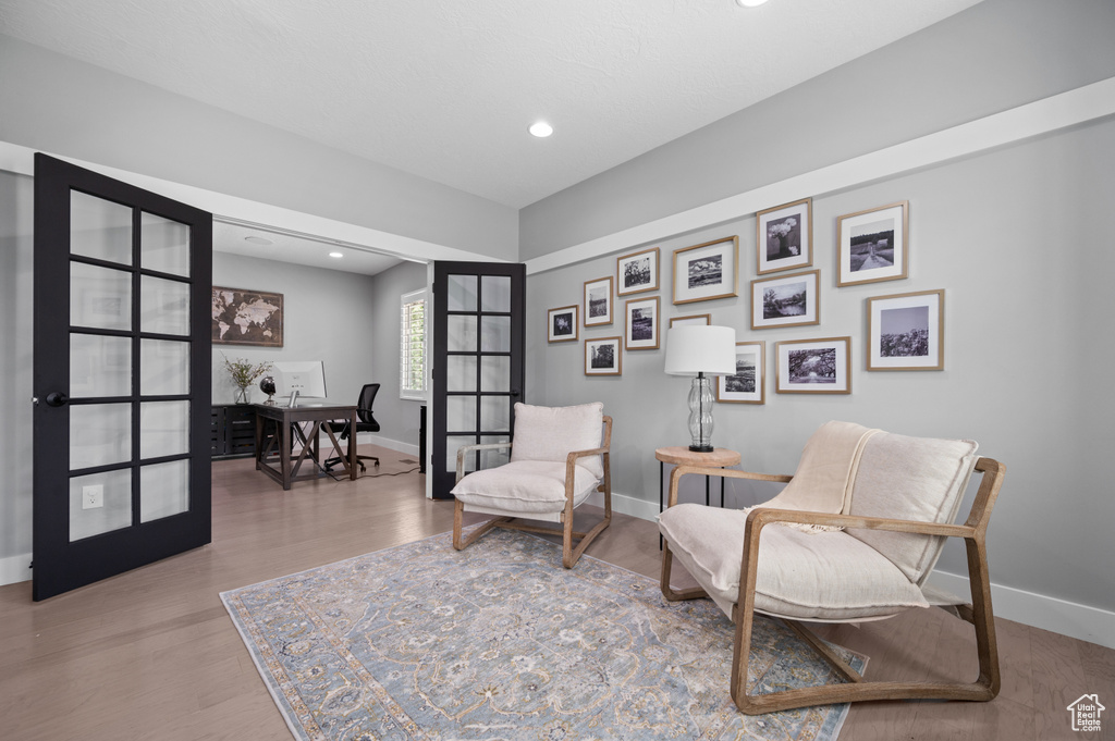 Sitting room with wood finished floors, a desk, recessed lighting, and french doors