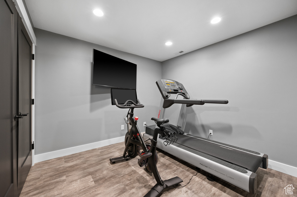 Exercise area with light wood finished floors and recessed lighting