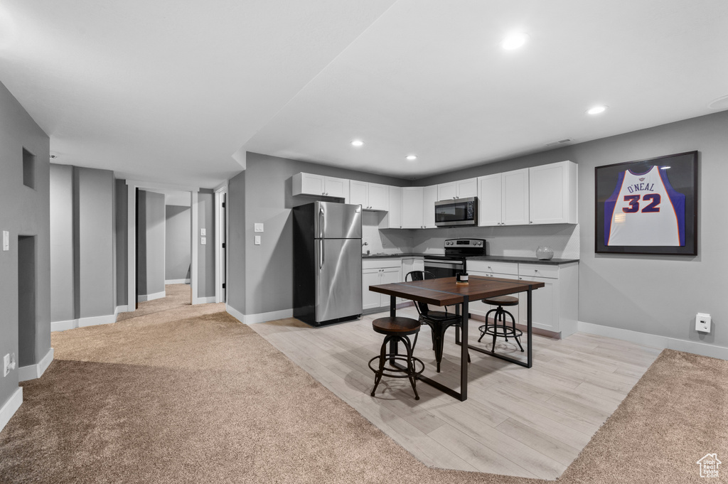 Kitchen with appliances with stainless steel finishes, recessed lighting, white cabinetry, light wood-style floors, and dark countertops