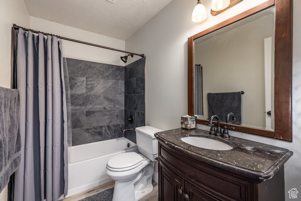 Bathroom with shower / bath combination with curtain, vanity, and a textured ceiling